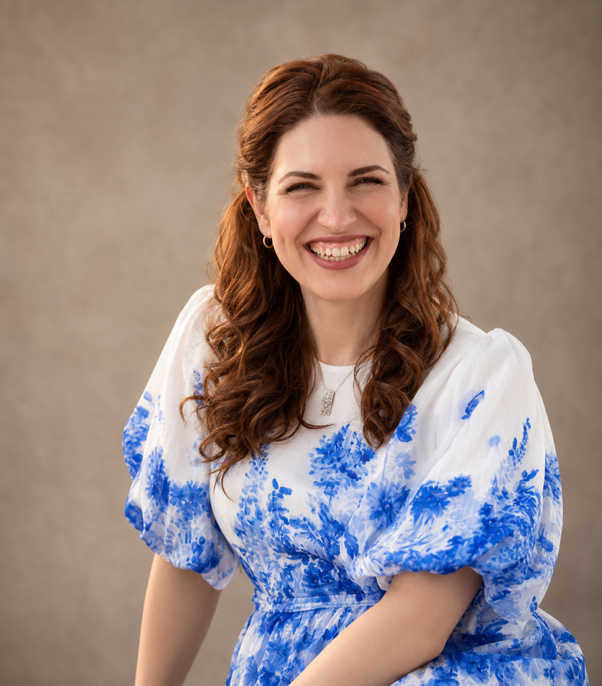Studio portrait of Dr. Neda Maria Kaizumi smiling in a blue floral dress