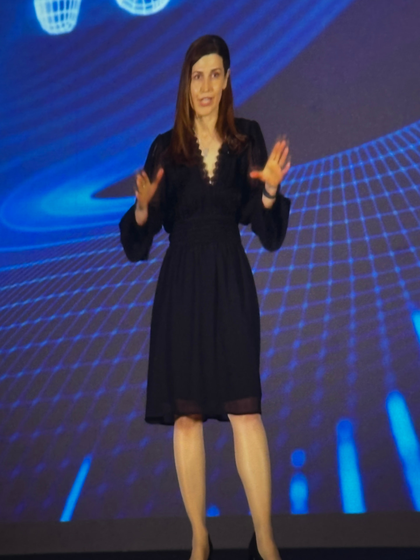 Dr. Neda Maria Kaizumi delivering a keynote on a large conference stage