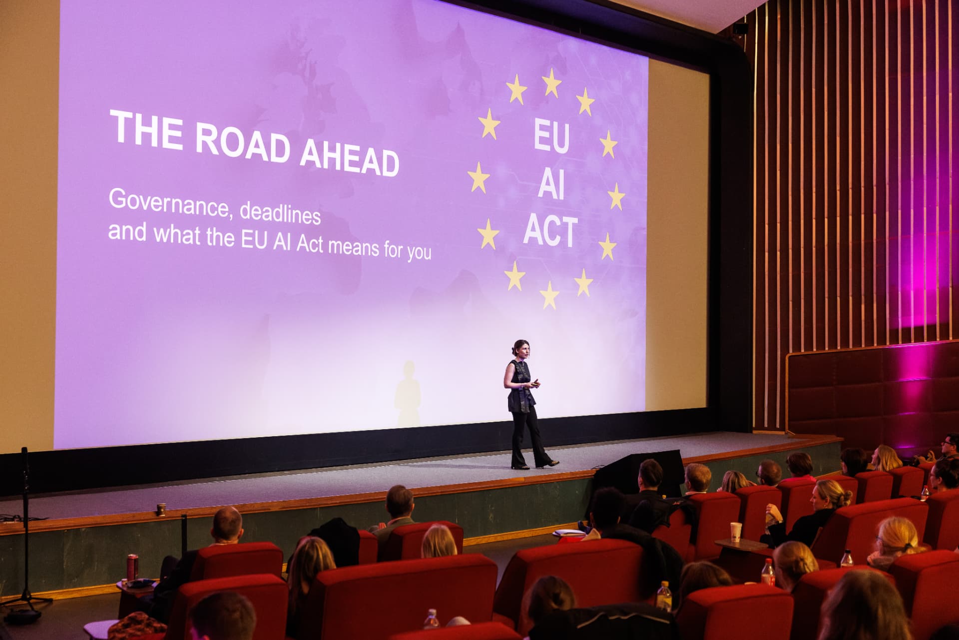 Dr. Neda Maria Kaizumi presenting "The Road Ahead — the EU AI Act" to a full auditorium